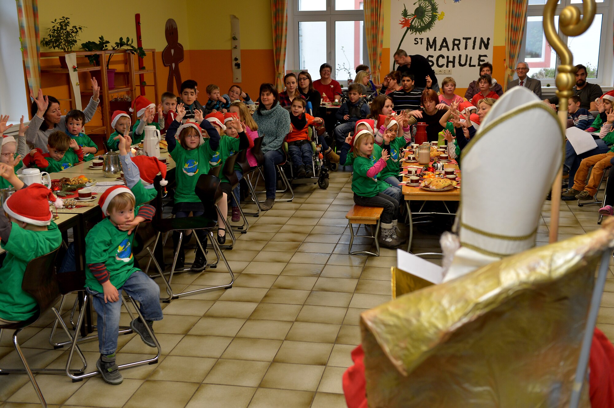 Sankt Nikolaus sits on a golden chair and reads to children from St. Martin School in Bitburg, Germany, Dec. 8, 2014. St. Martin School invited Airmen from Spangdahlem Air Base, Germany, to join the children in celebration with Sankt Nikolaus. The Airmen passed out presents and candy to the children after meeting Sankt Nikolaus. (U.S. Air Force photo by Airman 1st Class Kyle Gese/Released)
