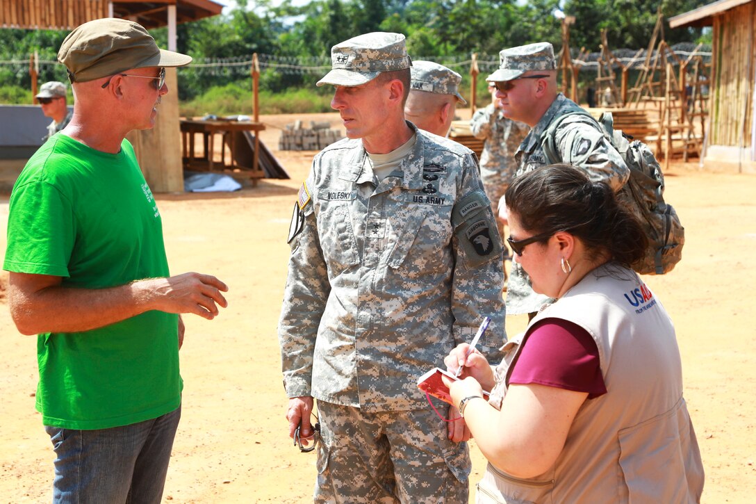 Thomas ten Boers, from left, project manager for Welt Hunger Hilfe; Maj. Gen. Gary Volesky, commander of Joint Forces Command – United Assistance and Mia Beers, team lead for the Disaster Assistance Response Team with the U.S. Agency for International Development discuss the final construction plans for an Ebola treatment unit being built in support of Operation United Assistance in Zwedru, Liberia, Dec. 10, 2014. 