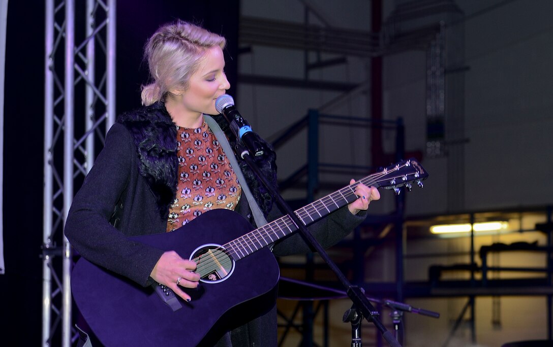 Dianna Agron, singer and actress, performs for audience members during the USO holiday Troop Visit on Royal Air Force Mildenhall, England, Dec. 10, 2014.