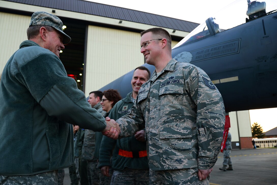 U.S. Army Gen. Martin E. Dempsey, left, chairman of the Joint Chiefs of Staff, gives U.S.Air Force Tech. Sgt. Scott Douglass a coin with his handshake during the USO Holiday Troop Visit on Royal Air Force Mildenhall, England, Dec. 10, 2014. USO traditionally partners with senior leaders and celebrity entertainers to visit troops serving abroad during the holiday season. Douglass is an assistant flight chief assigned to the 48th Equipment Maintenance Squadron.