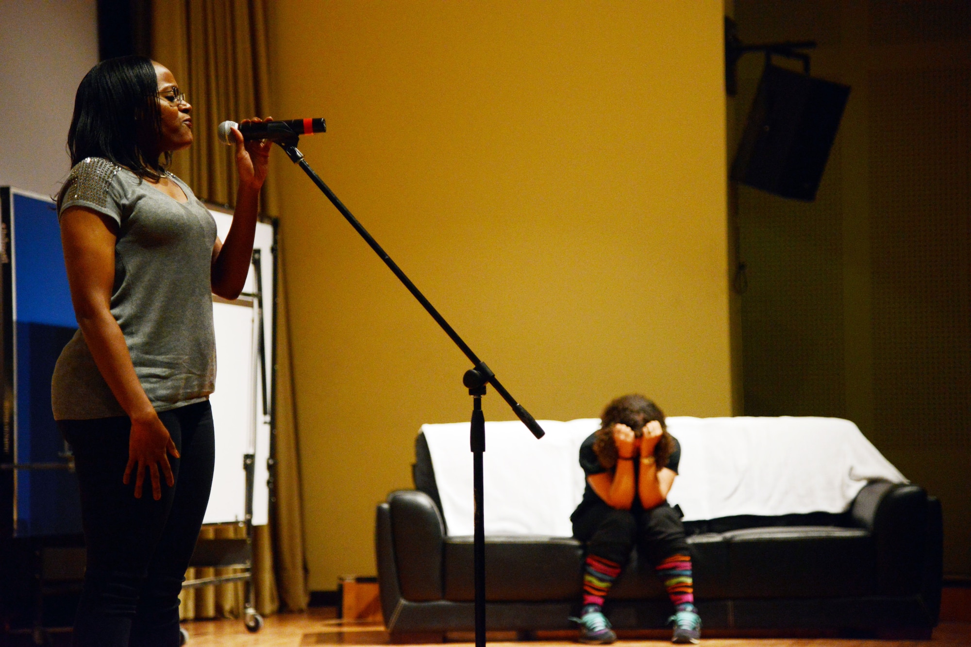 SOUTHWEST ASIA - Staff Sgt. Sikina Black sings "Angel" by Sarah McLachlan following one of the skits performed by the 386th Air Expeditionary Wing Sexual Assault Prevention and Response team here Dec. 9, 2014. In the background, Staff Sgt. Ashley Gonzales, one of the actors, portrays a sexual assault victim. The performance featured five skits related to sexual assault and harassment and eight vocal and poetry performances. (U.S. Air Force photo by Tech. Sgt. Jared Marquis/released)