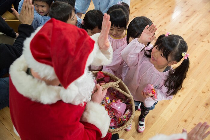 A volunteer from Marine Corps Air Station Iwakuni, Japan, dressed as Santa Claus, hands out candy to the children at Josho Hoikuen during a community relations preschool visit, Dec. 9, 2014. The purpose of this event was to interact with the local community in a gesture of goodwill and strengthen the bond between the U.S. and Japan.