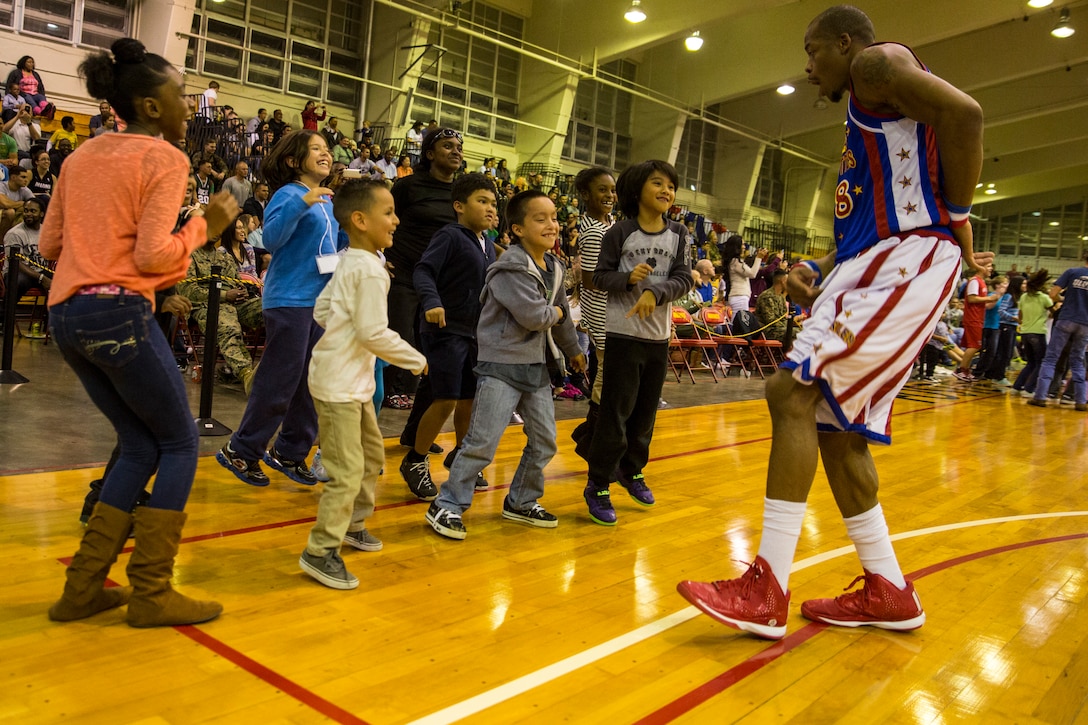 Harlem Globetrotters forward, Eric ‘Hackshaw’ Hall, right, dances with children Dec. 9 at the Foster Field House on Camp Foster. The Harlem Globetrotters displayed their basketball artistry to service members and their families. The Harlem Globetrotters are more than a basketball show; they incorporate high flying acrobat dunks with comedic skits to provide enjoyment for all ages. The event was a part of the Harlem Globetrotters 13th military tour, in which the team travels overseas to U.S. military installations to provide memories of home during the holidays. The game was presented by Navy Entertainment, Leatherneck Tour and Marine Corps Community Services.