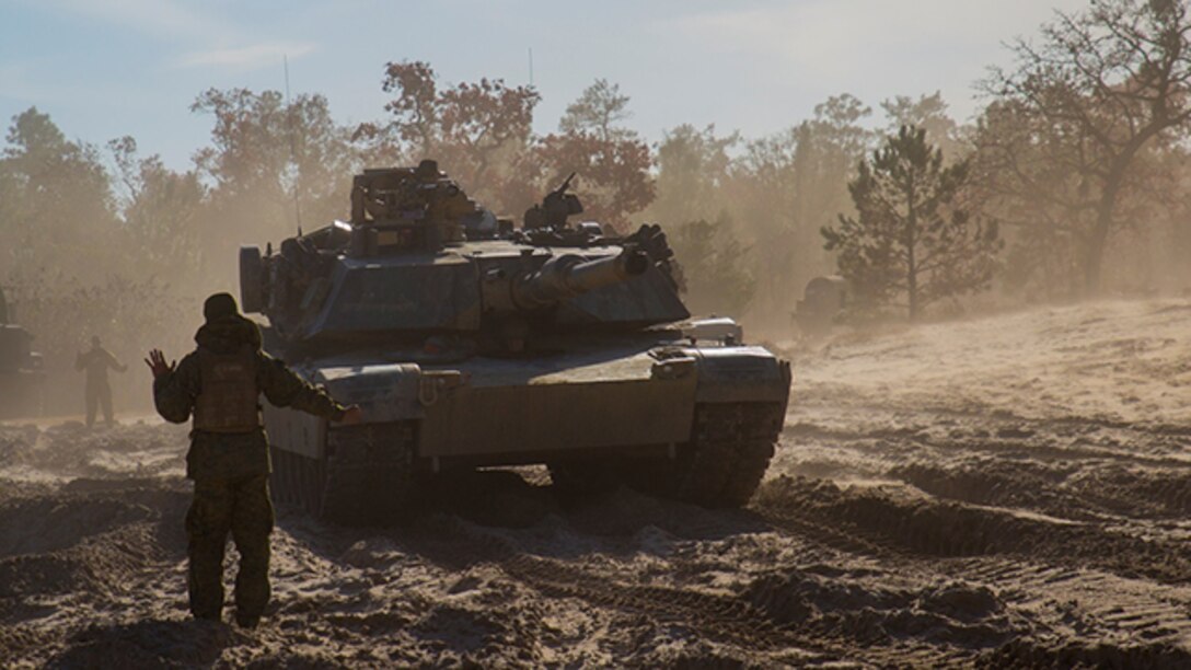 Cpl. Jose Peralta, a Marine with Company B, 2nd Tank Battalion, 2nd Marine Division, guides a tank into a lane after conducting breaching exercises aboard Marine Corps Base Camp Lejeune, North Carolina, Dec. 8. Marines with 2nd Tank Battalion along with 2nd CEB worked together to conduct breaching exercises in which they provided support fire while Assault Breacher Vehicles eliminated tank pits and created a lane in which tanks may safely travel, aboard Camp Lejeune, Dec. 8-10.