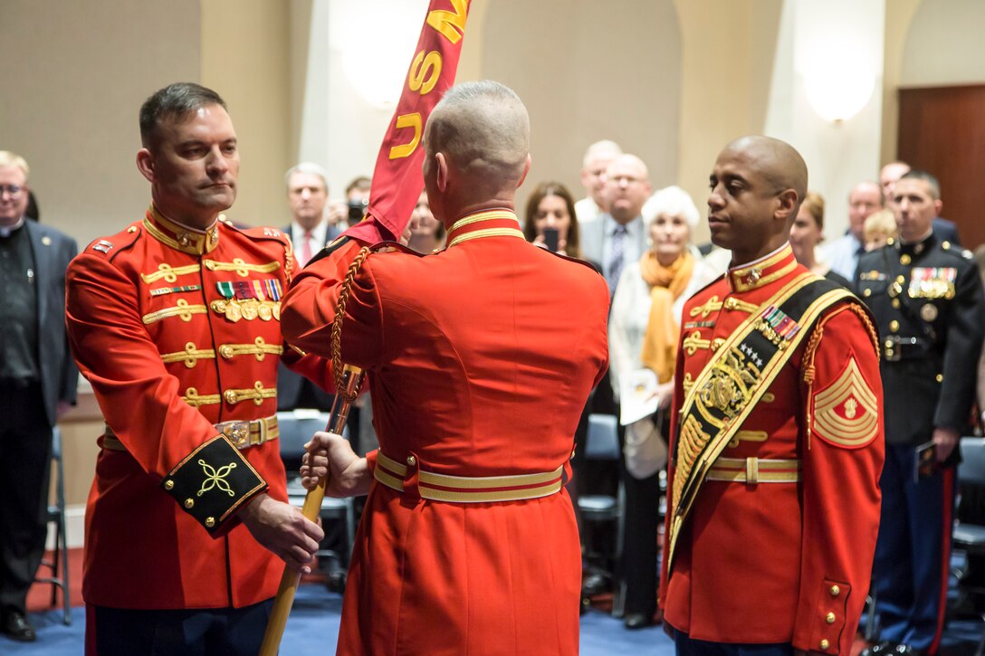 Maj. Brian Dix, outgoing commanding officer of "The Commandant's Own," The United States Marine Drum & Bugle Corps, passes the unit's guidon to Capt. Christopher Hall, incoming commanding officer, during a change of command ceremony at Marine Barracks Washington, D.C., Dec. 11, 2014. Dix was appointed as the fourth director of "The Commandant's Own," in September 1998. Hall joined "The Commandant's Own" in March 1994 as a mellophone bugler, and is the only officer to serve as a Drum Major, Assistant Director, Operations Officer and Executive Officer for the unit.