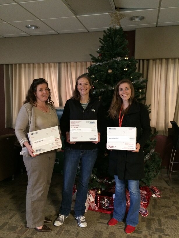 Icy Munchel, left, Megan Goold, center, and Katie Contento pose in front of a Christmas tree at Marine Corps Air Station Cherry Point, N.C., Dec. 6, 2014. The In-Service Support Center activities team donated more than 118 care packages to Cherry Point Marines and Sailors deployed to Moron, Spain with Marine Aerial Transport Squadron 252. Munchel is the family readiness officer with VMGR-252; Goold is a chemist with Naval Air Systems Command; and Conento is a T-64 engineer with NAVAIR.
