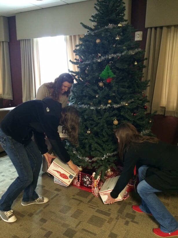 Icy Munchel, left, Megan Goold, center, and Katie Contento place care packages under a Christmas tree at Marine Corps Air Station Cherry Point, N.C., Dec. 3, 2014. Members of the In-Service Support Center with the Fleet Readiness Center East at Cherry Point donated more than 118 care packages to Marines and Sailors with Marine Aerial Refueler Transport Squadron 252. The packages contained toiletries, comfort items and video games. Munchel is the family readiness officer with VMGR-252; Goold is a chemist with Naval Air Systems Command; and Conento is a T-64 engineer with NAVAIR.