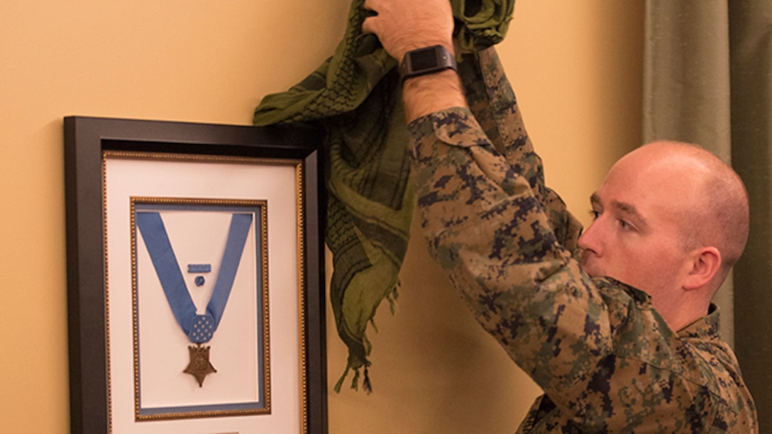 Petty Officer 2nd Class Timothy Martin, religious program specialist for The Basic School at Marine Corps Base Quantico, unveils Lt. Vincent Capodanno's Medal of Honor during the dedication ceremony at the Capodanno Chapel aboard The Basic School, Marine Corps Base Quantico, Virginia, December 9, 2014. Chaplain Capodanno served with 3rd Battalion, 5th Marine Regiment in the Vietnam War and was awarded the Medal of Honor posthumously for his actions.