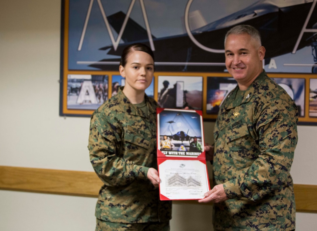 Sgt. Erika M. Cruz, the non-commissioned officer-in-charge at the military post office on Marine Corps Air Station Yuma, Ariz., receives her promotion warrant after she was meritoriously promoted by Col. Ricardo Martinez, the station commanding officer, following her selection as Marine of the Year for Marine Corps Installations West, Monday, Nov. 3, 2014.
