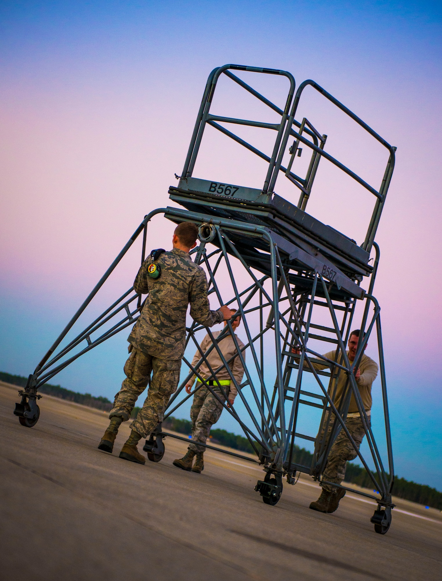 Airmen from the 15th Aircraft Maintenance Unit move a maintenance stand to work on a MC-130 Talon II at Hurlburt Field, Fla., Dec. 8, 2014. The mission of the aircraft involves a global, day and night, adverse weather capability to insert, extract and supply special operations by low or high altitude airdrop or land operations. (U.S. Air Force photo/Senior Airman Meagan K. Schutter)