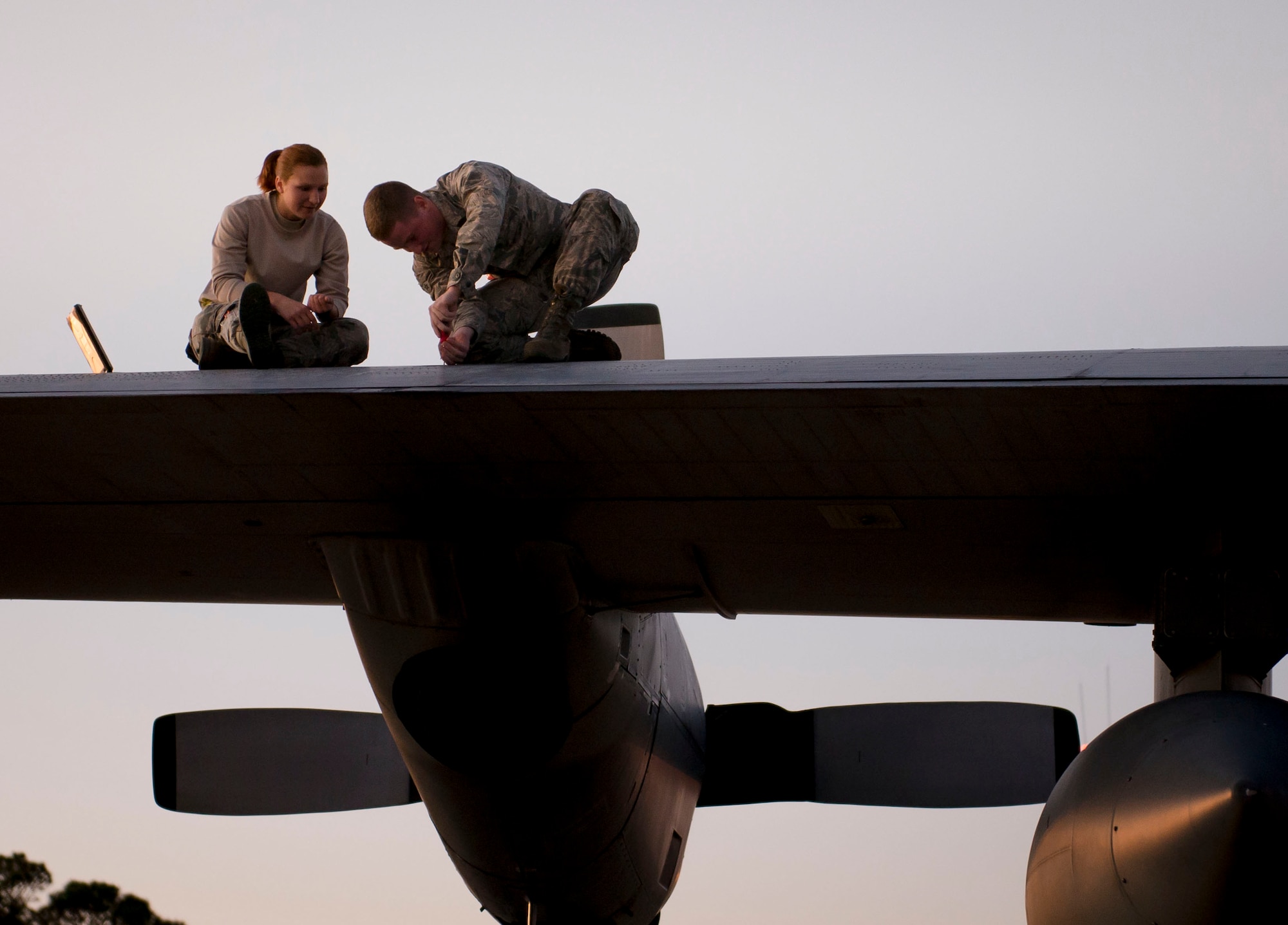 Airmen 1st Class Travis Venden and Kristen Markey, 15th Aircraft Maintenance Unit electrical and environmental technicians, perform electrical maintenance on the wing of a  MC-130 Talon II at Hurlburt Field, Fla., Dec. 8, 2014. The aircraft is specially modified to support unconventional warfare and special operations forces worldwide. (U.S. Air Force photo/Senior Airman Meagan K. Schutter)