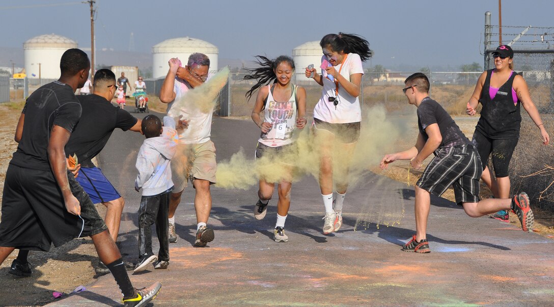 Runners are dowsed by volunteers with color as they round the last station before crossing the finish line during the 5K Fun Color Run Aug. 9, hosted by the 452nd Air Mobility Wing Rising Six. More than 100 Team March members participated in two color runs, held at the former base track, one during each August Unit Training Assembly. (U.S. Air Force photo/Tech. Sgt. Megan Crusher)