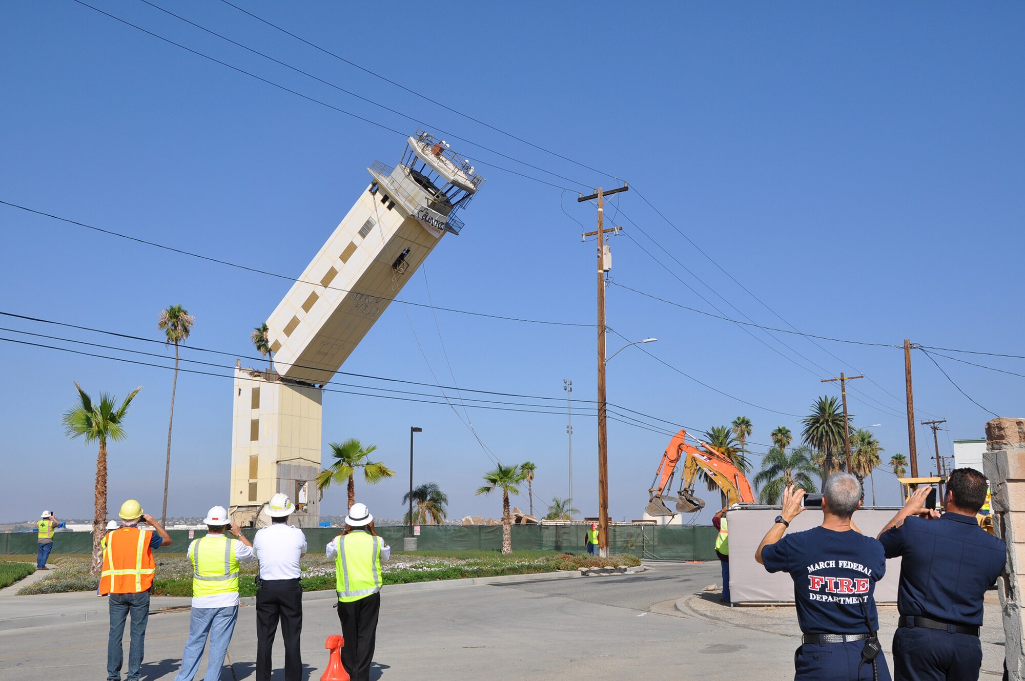 Team March members look on as contractors expertly topple the 56-year-old air traffic control tower at March Air Reserve Base, Calif.. Replaced by a new, seismically-engineered tower, the old tower hit the ground at 9:20 a.m., Aug. 19, 2014. (U.S. Air Force photo/Linda Welz)
