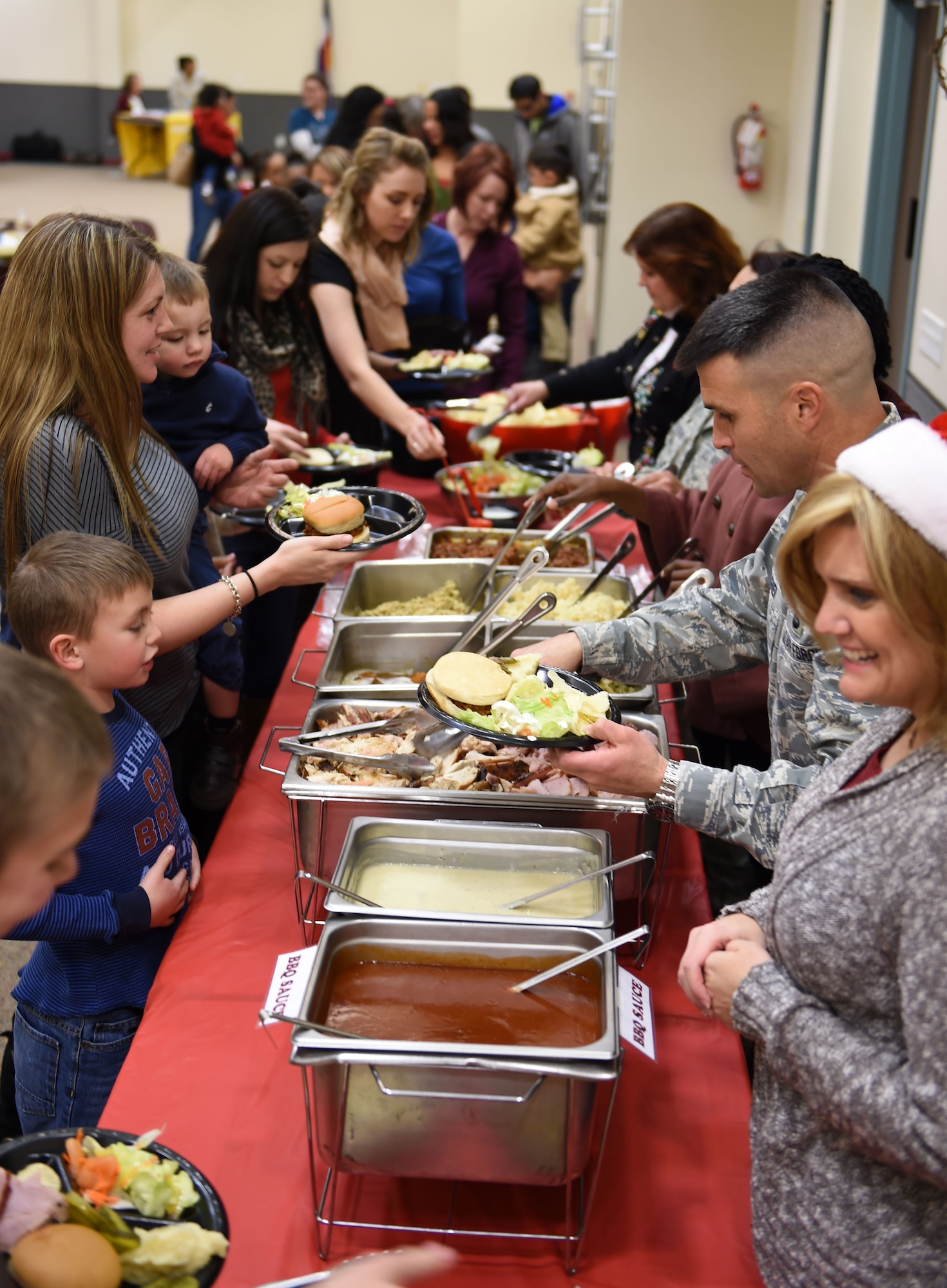 Base leadership serve a holiday meal to families of deployed Airman during the Hearts Apart Family Holiday Dinner event Dec. 11, 2014, at the 140th Wing dining facility on base. At the event, the families received stockings filled with presents and raffle drawings throughout the night. (U.S. Air Force photo by Airman 1st Class Emily E. Amyotte/Released)