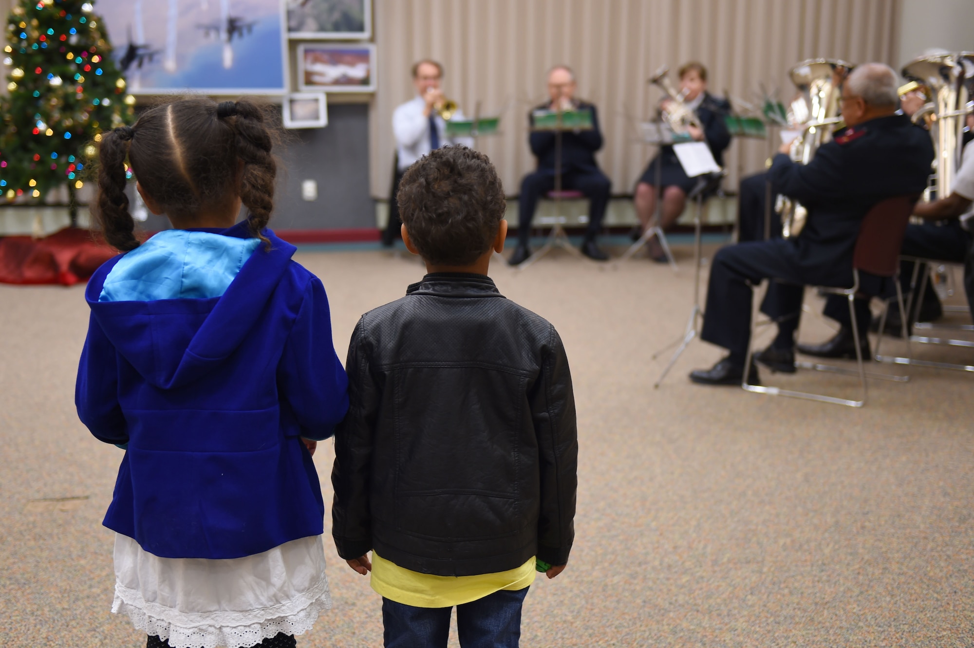 Children listen as a live band performs Christmas songs at the Hearts Apart Family Holiday Dinner event Dec. 11, 2014, at the 140th Wing dining facility on base. The band took the children’s’ requests to play their favorite Christmas tune and played for them. (U.S. Air Force photo by Airman 1st Class Emily E. Amyotte/Released)