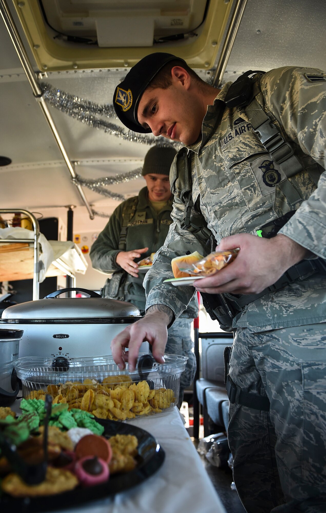 Airman 1st Class Travis Fiero, 460th Security Forces Squadron, gets some grub on the 460th Mission Support Group’s holiday party bus Dec. 11, 2014, on Buckley Air Force Base, Colo. During their route, the holiday party bus crew made stops at 19 support group work areas while distributing food and holiday greetings. Some of the 460th MSG agencies the bus visited were the fire department, outdoor recreation and child development centers and security forces, civil engineer, and force support squadrons. (U.S. Air Force photo by Senior Airman Riley Johnson/Released)