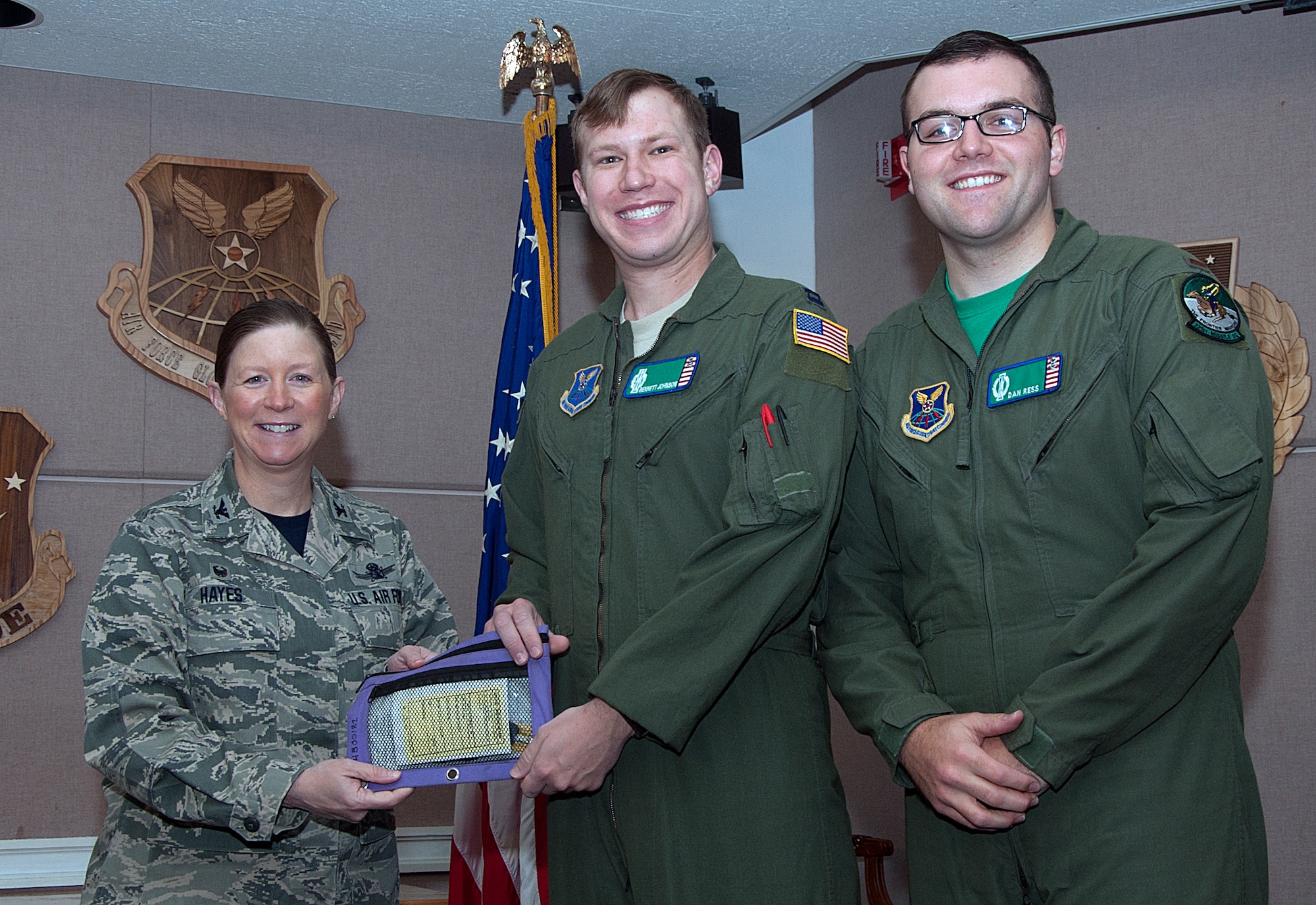 Capt. Bennett Johnson and 2nd Lt. Dan Ress, 321st Missile Squadron missileers, pose with Col. Tracey Hayes, 90th Missile Wing commander, as she presents them the keys to a new government-owned vehicle Dec. 5, 2014, in the 90th Operations Group pre-departure room, F.E. Warren Air Force Base, Wyo. Johnson and Ress were one of two sets of missileers to use one of the new trucks when traveling to the missile field. (U.S. Air Force photo/Airman 1st Class Brandon Valle)