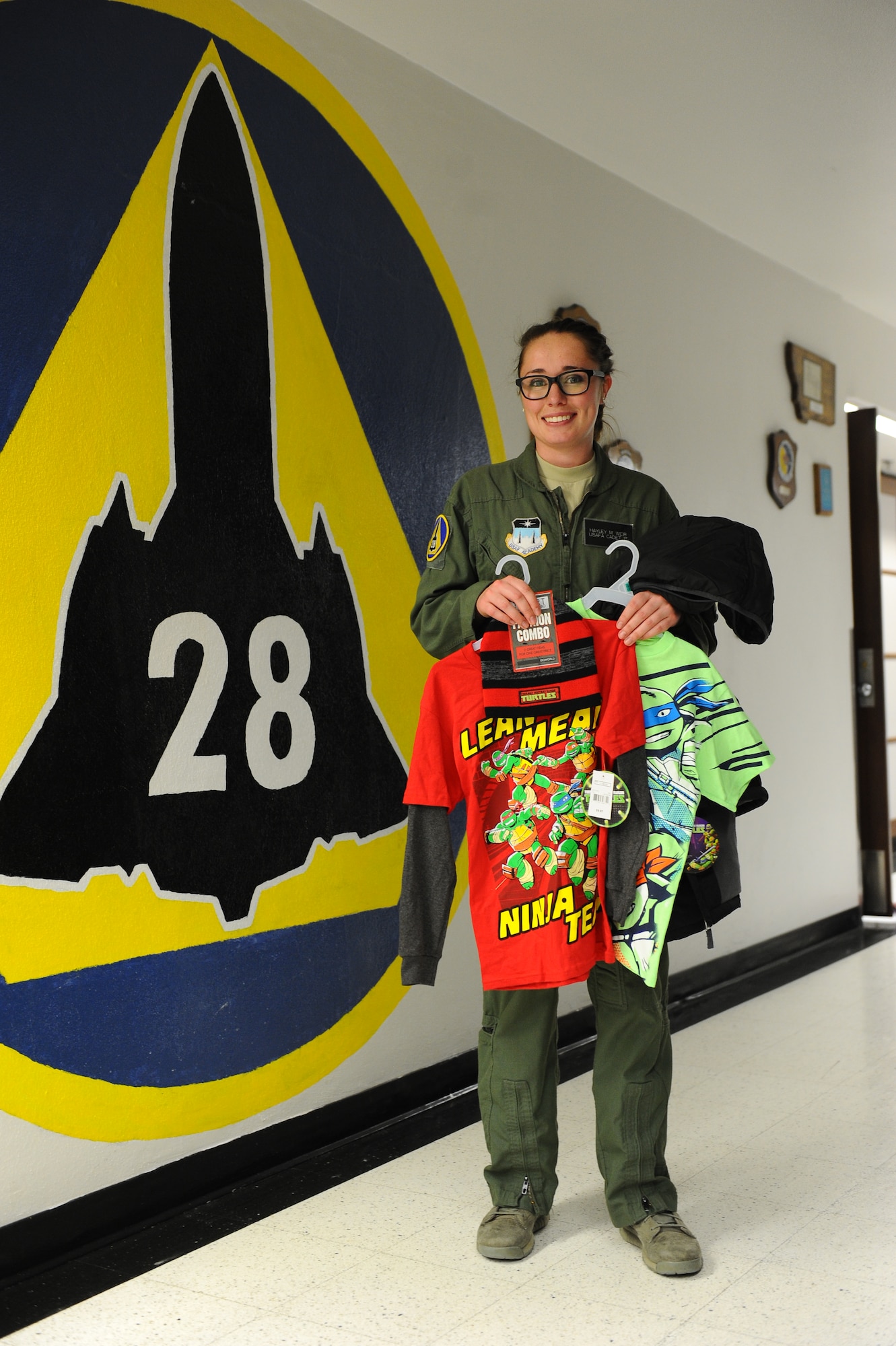 Cadet 3rd Class Hayley Weir, Cadet Squadron 28, holds up clothing bought for two local families through a holiday gift adoption program at her squadron Dec. 12, 2014. Weir, the squadron's character officer, organized the project, which was funded solely through private cadet donations. (U.S. Air Force photo/Airman 1st Class Rachel Hammes)