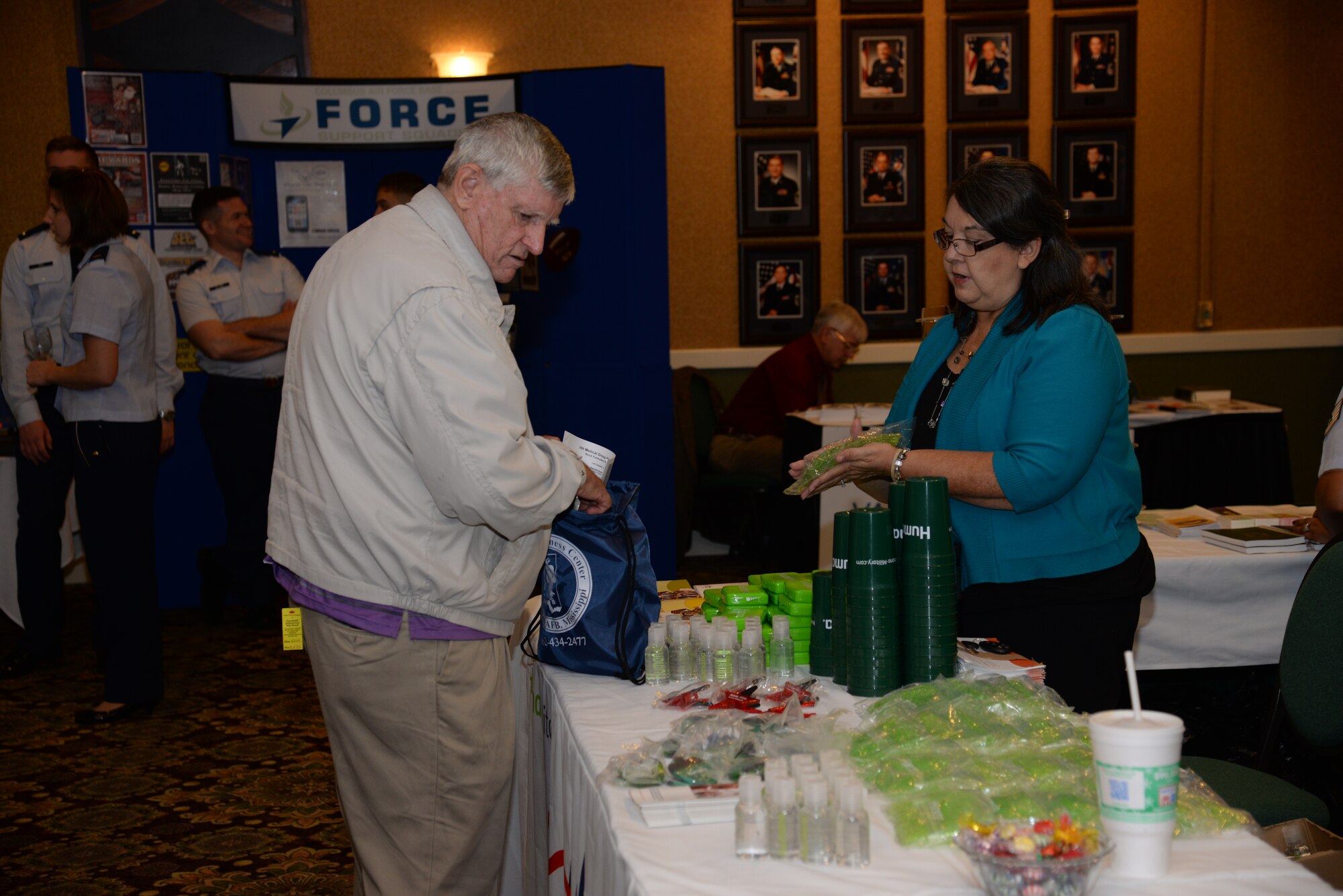 Dee Bond, Tricare Benefits Advisor, talks to a local retiree about Tricare while emonstrating how to use the free small useful medical items such as gel packs and first aid kits they were giving away during a Retiree Appreciation Day Dec. 6. Other booths at the retiree event included the 14th Force Support Squadron, the 14th Medical Group, and the 14th Flying Training Wing Chapel. (U.S. Air Force Photo/Senior Airman Stephanie Englar)