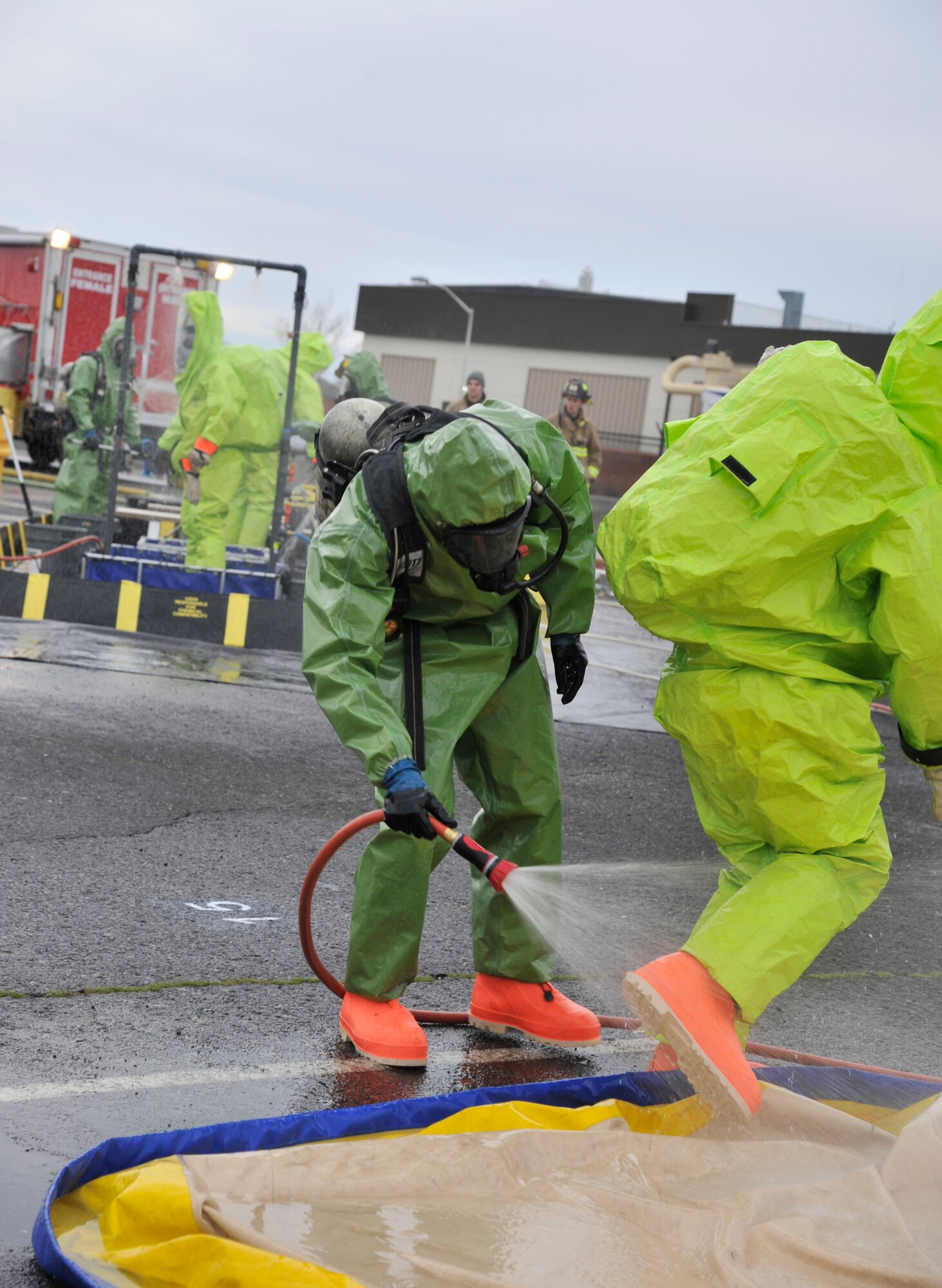 A decontamination team member sprays another exercise participant down during a mutual-aid hazardous materials emergency response exercise Dec. 10, 2014, at Fairchild Air Force Base, Wash. This four day exercise consisted of around 40-60 members each day from Fairchild and the Spokane, Wash. community fire and HAZMAT response teams. Scenarios used during the exercise varied from train derailments to a gas leaked inside the heating and ventilation systems of a building. (U.S. Air Force photo/Senior Airman Mary O'Dell)