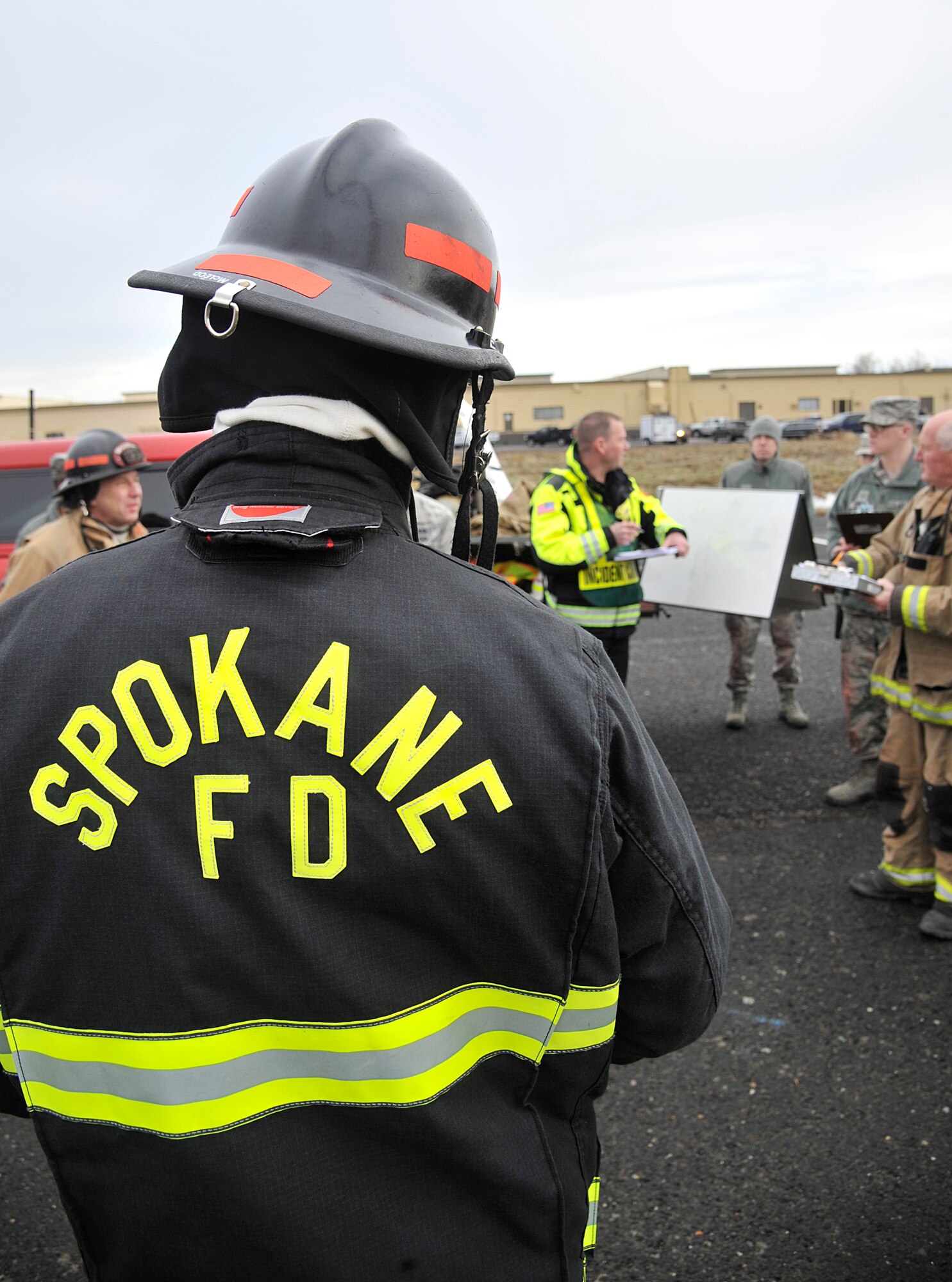 Members of the Spokane, Wash. fire department receive a mission briefing with Team Fairchild emergency responders during a hazardous materials emergency response exercise Dec. 10, 2014, at Fairchild Air Force Base, Wash. During the four day exercise, Airmen and local agencies came together to practicing scenarios such as train derailments and gas leaks through building ventilation systems. This is the first time these agencies have worked together in a training environment since the 1990s. (U.S. Air Force photo/Senior Airman Mary O'Dell)