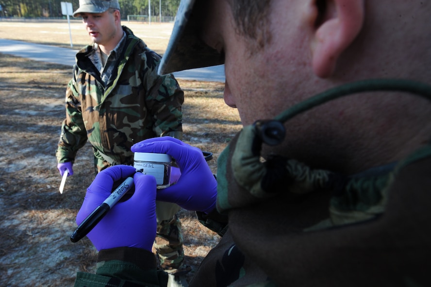 A U.S. Air Force Airman writes on a contamination sample bottle during an integrated base emergency response capability training at Shaw Air Force Base, S.C., Dec. 11, 2014. The 20th Civil Engineer Squadron emergency management flight and the 20th Aerospace Medicine Squadron bioenvironmental flight were tested on their abilities to react and work together in the event a chemical attack were to happen on base. (U.S. Air Force photo by Airman 1st Class Michael Cossaboom/Released)