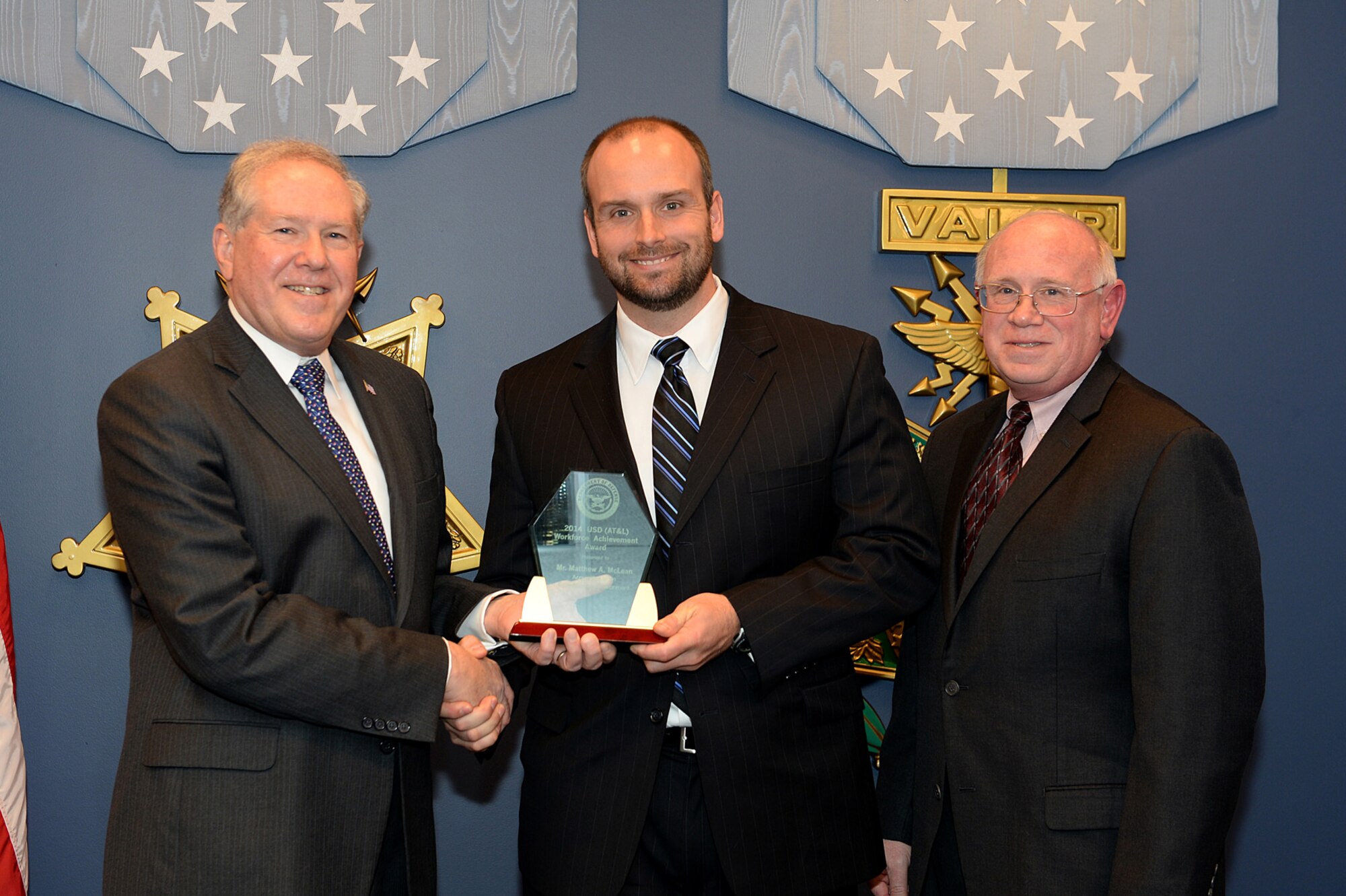 Under Secretary of Defense for Acquisition, Technology and Logistics Frank Kendall, left, presents Academy 10th Contracting Squadron contracting officer Matthew McLean with the 2014 Defense Acquisition Workforce Award for Contracting in an Expeditionary Environment during a ceremony in the Pentagon Hall of Heroes Dec. 9, 2014. Deputy Assistant Secretary of the Air Force (Acquisition) Richard W. Lombari, right, was present for the ceremony. (Courtesy photo)