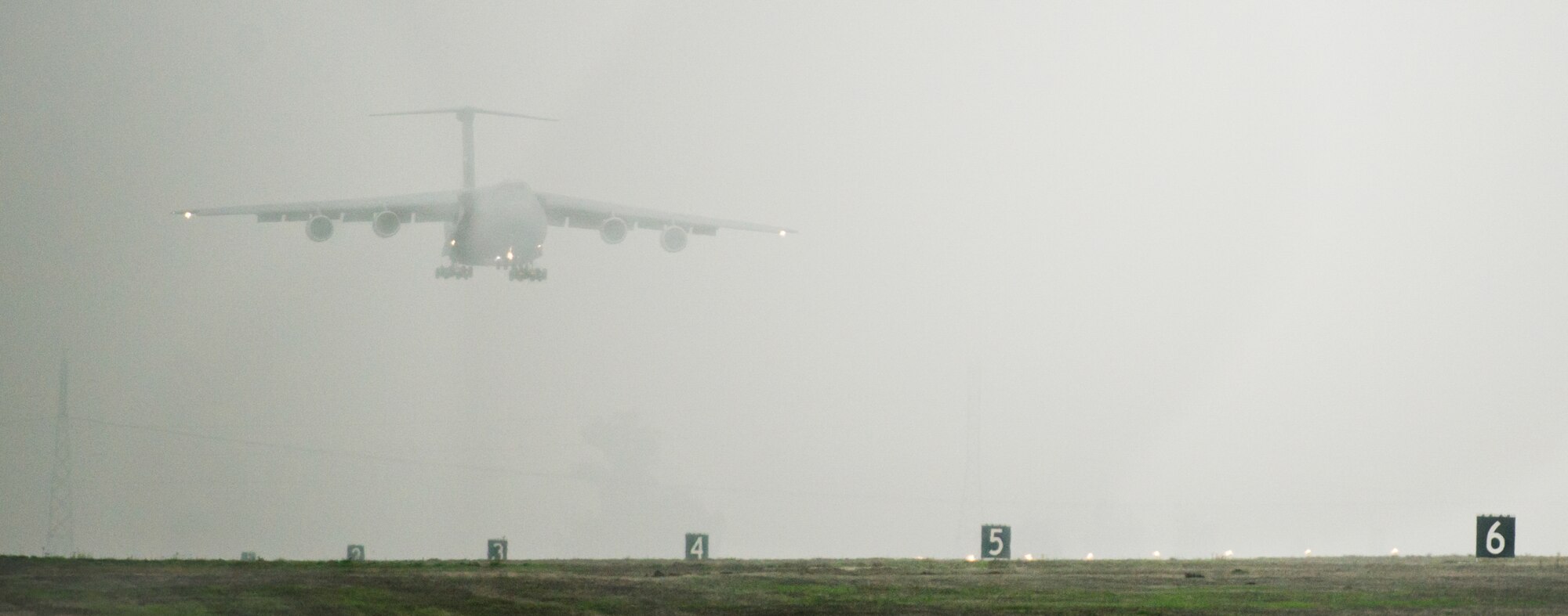 A C-5M Super Galaxy lands on a foggy runway at Travis AFB, Calif., Dec. 10, 2014. The newly-modernized aircraft is the fifth C-5M to return to Travis this year following retrograde and refurbishment.  According to Lockheed Martin, the improved strategic airlifter has set 43 world records and established new benchmarks in carrying more cargo faster and farther than any other plane. (Air Force photo/Ken Wright)