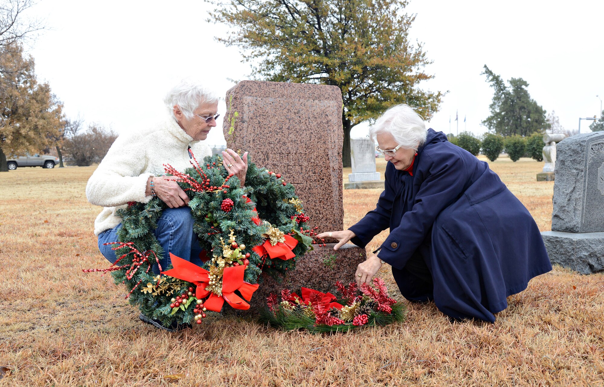 Lola Ames and Ruth Johnson, members of the National Society Daughters of the American Revolution Malcolm Hunter Chapter of Moore, place wreaths at the graves of veterans in Kuhlman Cemetery, just inside the Tinker Gate, on Dec. 4. The organization participates in the national program, Wreaths Across America, honoring fallen Soldiers with the wreaths each December. (Air Force photo by Kelly White)