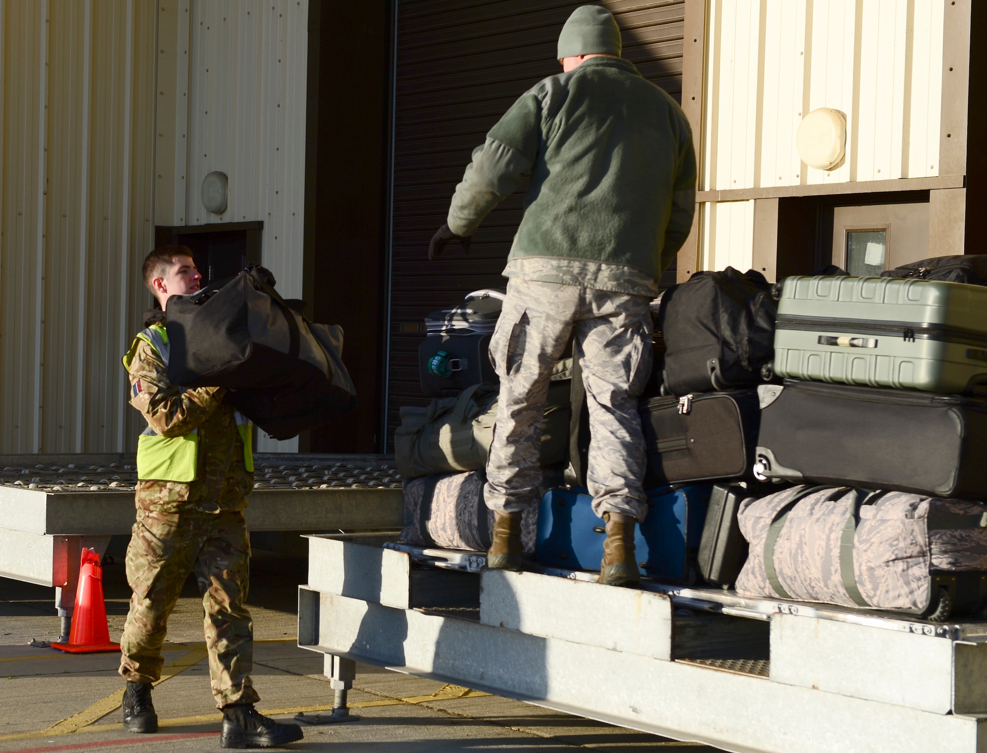 Royal Air Force and U.S. Air Force personnel prepare luggage to be loaded on Royal Air Force C-17A Globemaster III, Dec. 3, 2014 at Royal Air Force Lakenheath, England. The Movement Coordination Centre Europe program was established in 2007 recognizing shortages of Strategic Lift. (U.S. Air Force photo by Airman 1st Class Dawn M. Weber/Released)