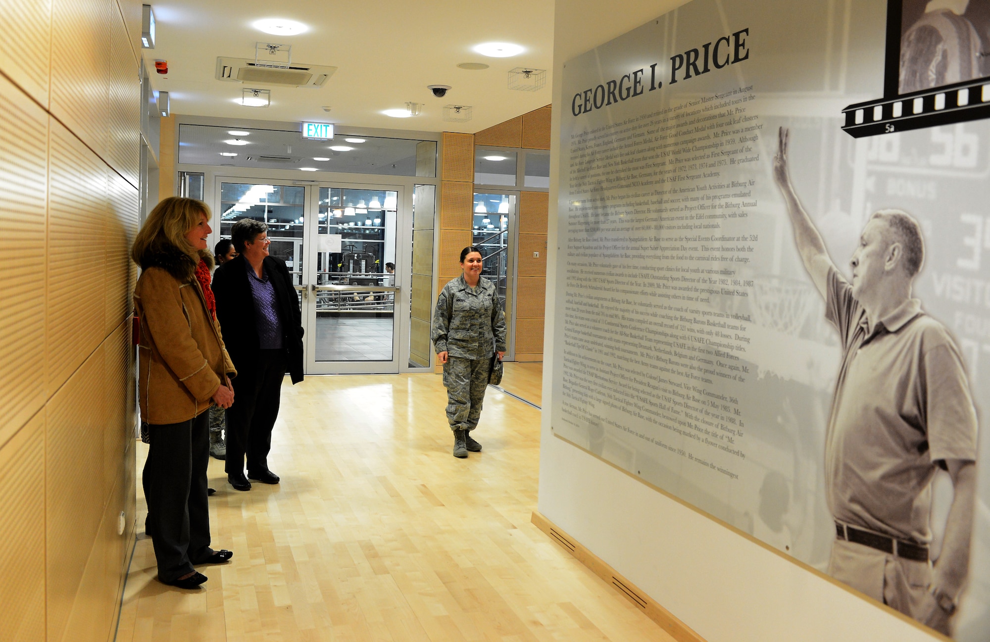 Cheryl Roberson, left, wife of U.S. Air Force Lt. Gen. Darryl Roberson, 3rd Air Force and 17th Expeditionary Air Force commander, reads the tribute to George Price in the George Price Gymnasium on Spangdahlem Air Base, Germany, Dec. 9, 2014. Roberson also attended the commander’s all call where her husband spoke on key Air Force issues. (U.S. Air Force photo by Airman 1st Class Luke Kitterman/Released)