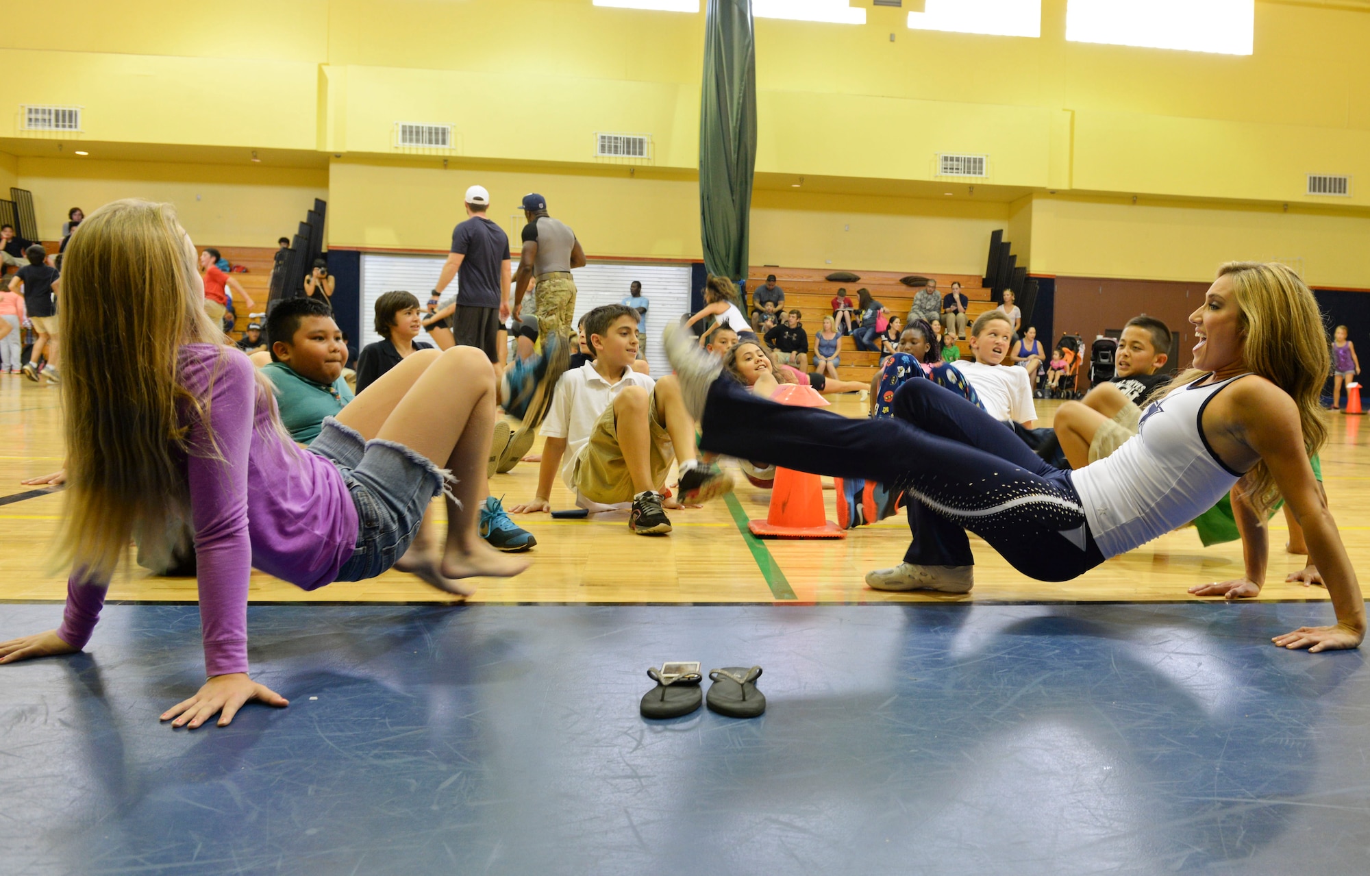 Team Andersen family members and a Dallas Cowboy cheerleader exercise Dec. 11, 2014, at Andersen Air Force Base, Guam. The cheerleaders held a meet and greet, performed, and participated in a workout session with the children at the youth center.  (U.S. Air Force photo by Staff Sgt. Robert Hicks/Released)   
