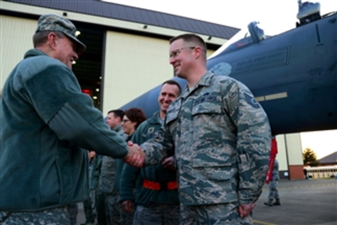 U.S. Army Gen. Martin E. Dempsey, chairman of the Joint Chiefs of Staff, gives a challenge coin to U.S. Air Force Tech. Sgt. Scott Douglass during a USO holiday troop visit on Royal Air Force Mildenhall, England, Dec. 10, 2014. Dempsey visited the air base with the USO show troupe, which includes athletes, singers and actors. 