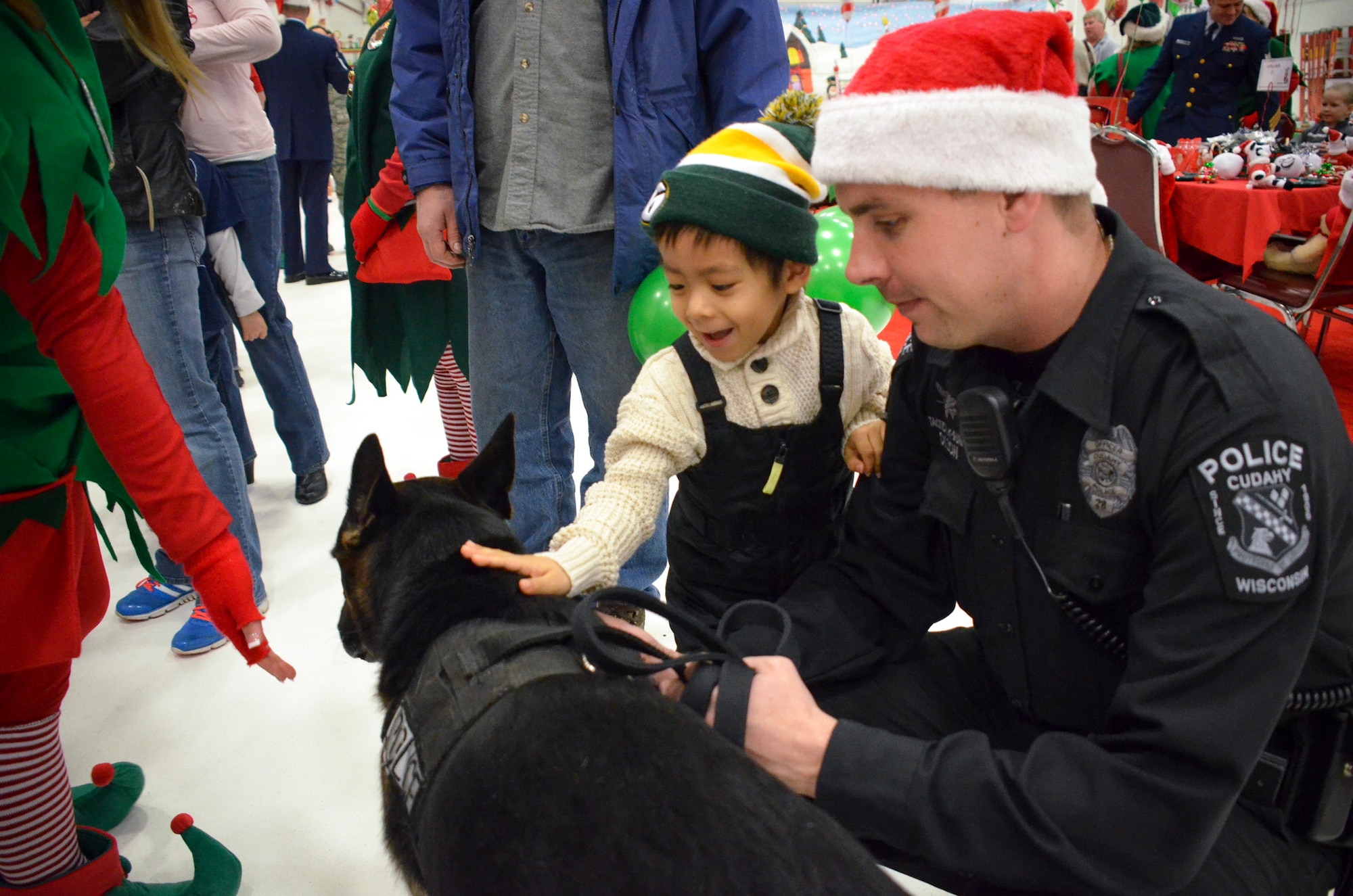 Sgt Brian Olson of the Cudahy Police Department lets children pet Ezzo, his k9 service dog, as they wait for Santa.  The annual Flight to the North Pole is hosted by the 128th Air Refueling Wing, Wisconsin Air National Guard, Milwaukee Dec. 13, 2014 here.  (U.S. Air National Guard photo by Master Sgt. Thomas J. Sobczyk/Released)
