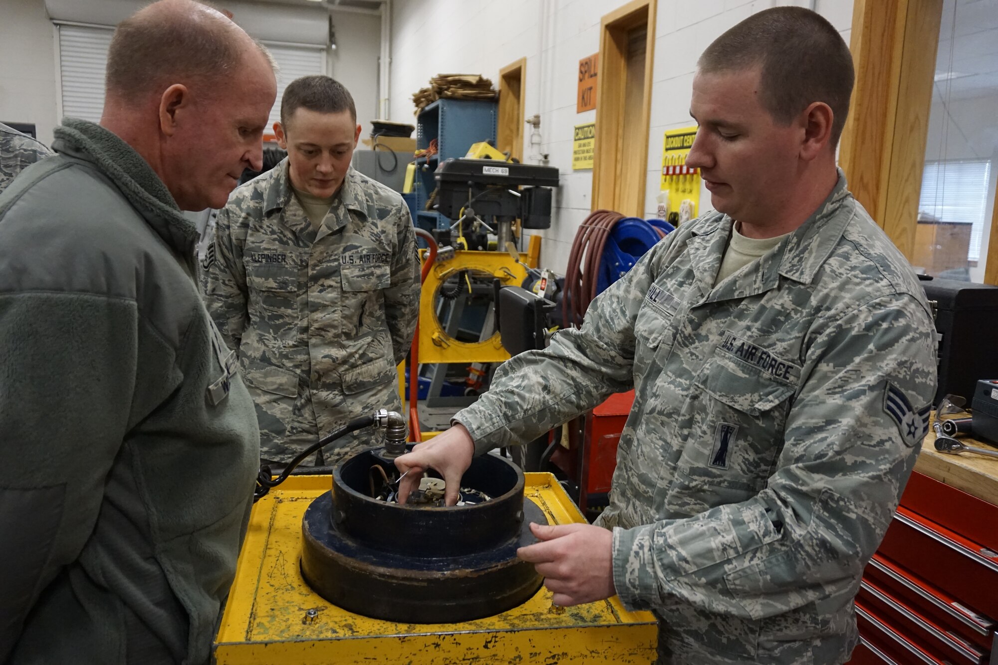 Senior Airman Brandin Hill, 90th Maintenance Operations Squadron, shows a security pit vault door to Lt. Gen. Stephen Wilson, Air Force Global Strike Command commander, as Staff Sgt. Dustin Klepinger, 90th Maintenance Operations Squadron, watches, Dec. 10, 2014. Wilson visited the 90th Missile Wing to check on the progress of the Force Improvement Program. (U.S. Air Force photo/Lan Kim)