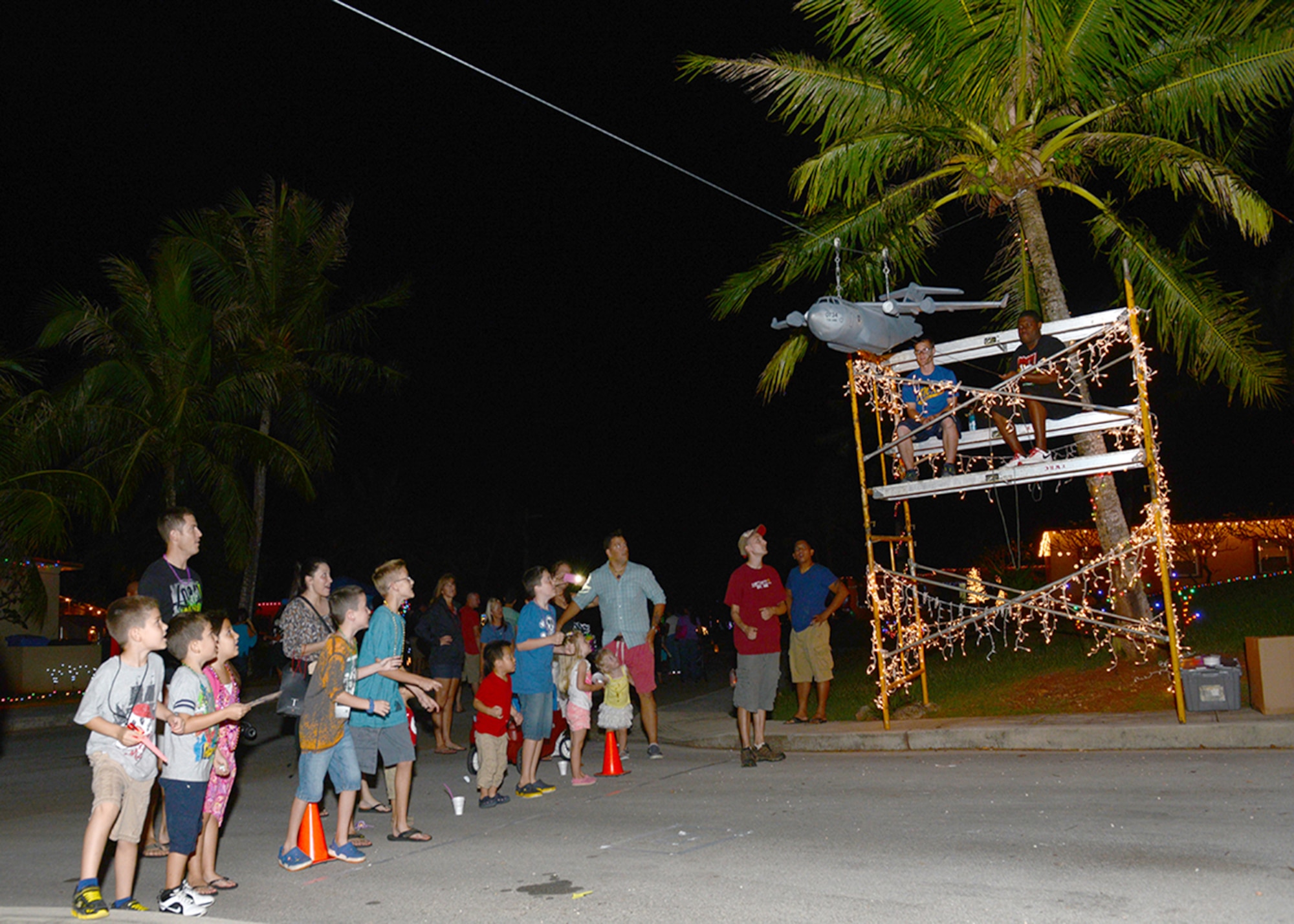 Team Andersen children wait for a model C-17 Globemaster III aircraft to drop candy during the base’s annual Rota Walk event Dec. 13, 2014, at Andersen Air Force Base, Guam.  Hundreds of military members and civilians attended the event which is held every December to showcase holiday decorations in the base housing area on Rota Drive. (U.S. Air Force photo by Tech. Sgt. Zachary Wilson/Released)