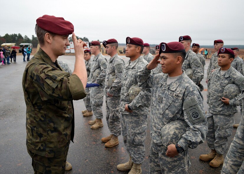A Polish paratrooper officer returns a salute from a U.S. Army paratrooper after the Soldier was presented with the Polish army parachute badge after jumping onto Sicily Drop Zone during the 17th Annual Randy Oler Memorial Operation Toy Drop on Dec. 6 at Fort Bragg, North Carolina. Operation Toy Drop is the world’s largest combined airborne operation where Soldiers donate a toy to receive a lottery ticket number that are then randomly drawn for an opportunity to train and jump with foreign jumpmasters over Sicily Drop Zone. Foreign jumpmasters from Poland, Italy, Latvia, Germany, Indonesia and the Netherlands participated in this year’s event. Last year, Operation Toy Drop collected more than 12,000 toys that were donated to local charities and organizations across North Carolina. (U.S. Air Force photo/Marvin Krause)