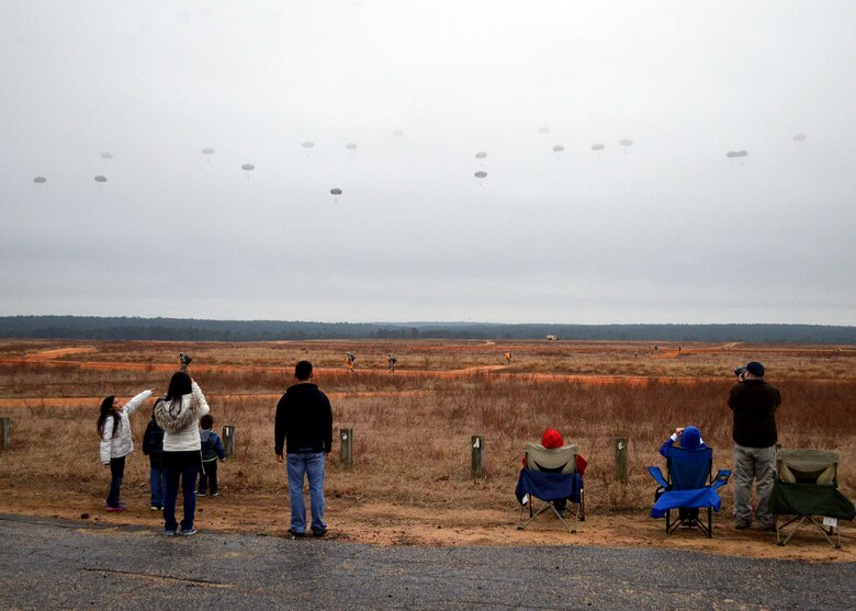 Spectators watch U.S. Army and foreign paratroopers jump at Sicily Drop Zone during the 17th Annual Randy Oler Memorial Operation Toy Drop on Dec. 6 at Fort Bragg, North Carolina. Operation Toy Drop is the world’s largest combined airborne operation where Soldiers donate a toy to receive a lottery ticket number that are then randomly drawn for an opportunity to train and jump with foreign jumpmasters over Sicily Drop Zone. Foreign jumpmasters from Poland, Italy, Latvia, Germany, Indonesia and the Netherlands participated in this year’s event. Last year, Operation Toy Drop collected more than 12,000 toys that were donated to local charities and organizations across North Carolina. (U.S. Air Force photo/Marvin Krause)