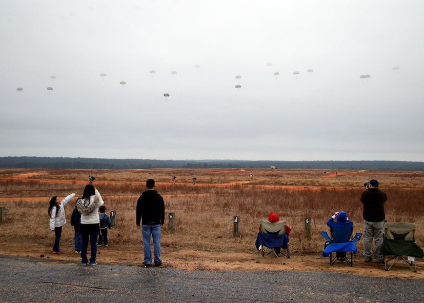 Spectators watch U.S. Army and foreign paratroopers jump at Sicily Drop Zone during the 17th Annual Randy Oler Memorial Operation Toy Drop on Dec. 6 at Fort Bragg, North Carolina. Operation Toy Drop is the world’s largest combined airborne operation where Soldiers donate a toy to receive a lottery ticket number that are then randomly drawn for an opportunity to train and jump with foreign jumpmasters over Sicily Drop Zone. Foreign jumpmasters from Poland, Italy, Latvia, Germany, Indonesia and the Netherlands participated in this year’s event. Last year, Operation Toy Drop collected more than 12,000 toys that were donated to local charities and organizations across North Carolina. (U.S. Air Force photo/Marvin Krause)