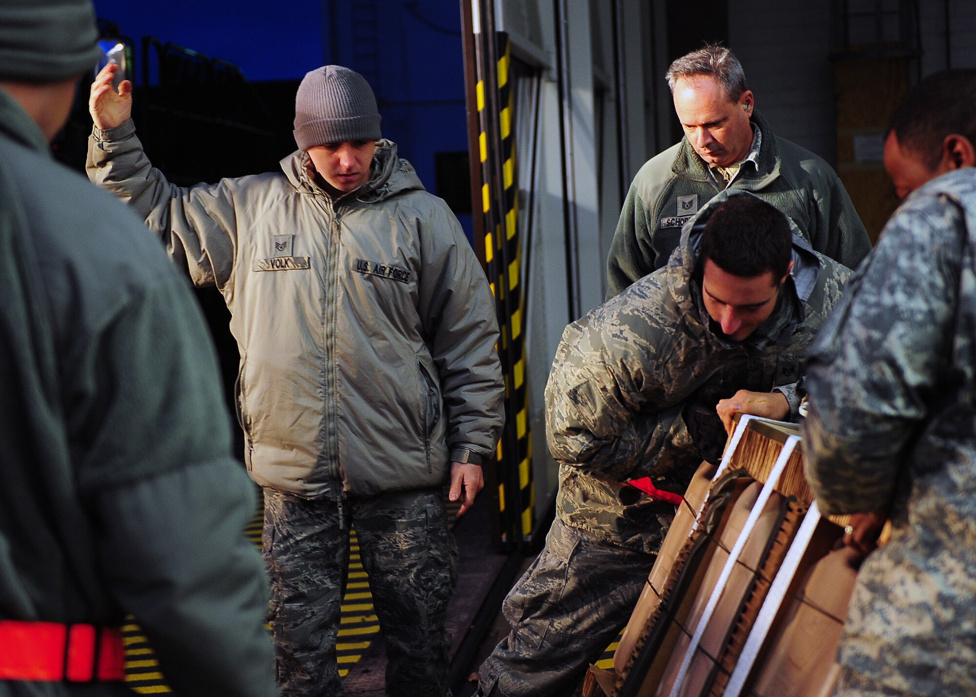 Staff Sgt. Matthew Volk guides fellow team members as they load a container specifically built for Santa Claus to deliver toys to children on Dec. 15, 2014, from Ramstein Air Base, Germany. Much like Santa’s elves, these Airmen and Soldiers were responsible for packing Santa’s sleigh, which happened to be a C-130J Super Hercules. Volk is a 86th Logistics Readiness Squadron aerial delivery technician. (U.S. Air Force photo/Staff Sgt. Kris Levasseur)