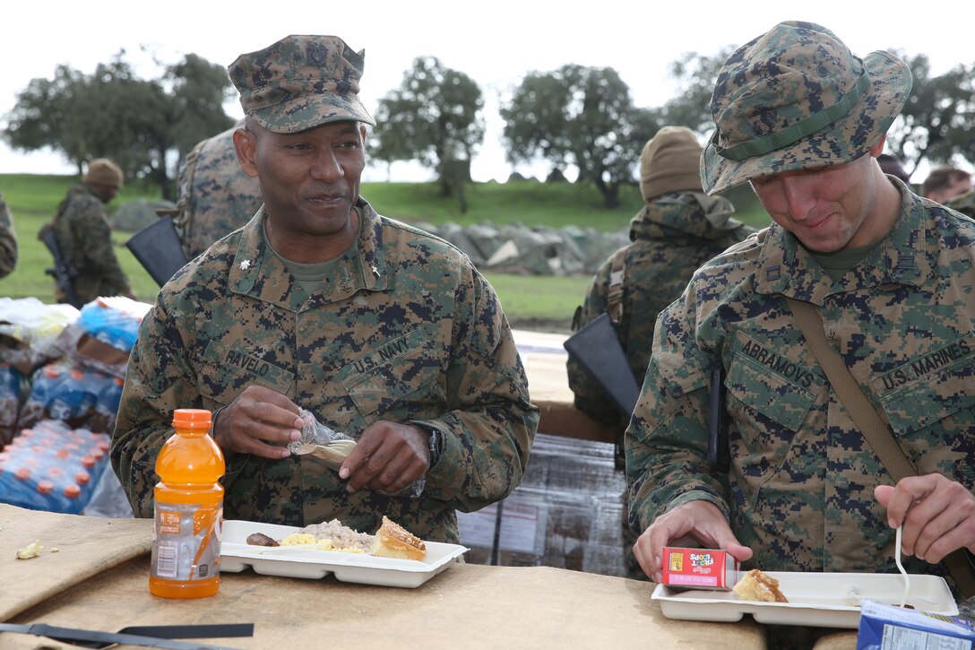 U.S. Navy Commander Samuel Ravelo, left, eats lunch with U.S. Marines from Headquarters and Service Company, Battalion Landing Team 3rd Battalion, 1st Marine Regiment, during realistic urban training aboard Camp Roberts, Calif., Dec. 12, 2014. Ravelo is the chaplain of the 15th Marine Expeditionary Unit. The purpose of RUT is to provide the MEU the opportunity to conduct training in unfamiliar environments in preparation for their upcoming deployment. (U.S. Marine Corps photo by Cpl. Anna Albrecht/ Released)