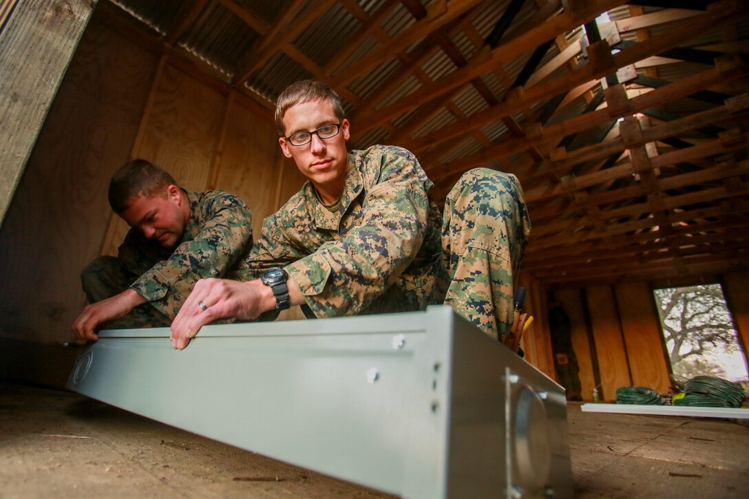 U.S. Marine Lance Cpl. Matt Neilsen, left, and Cpl. Michael Beck prepare a fuse box for installation in a Southwest Asia hut during realistic urban training aboard Fort Hunter Liggett, Calif., Dec. 14, 2014. Neilsen and Beck are combat engineers with Combat Logistics Battalion 15, 15th Marine Expeditionary Unit. RUT prepares the 15th MEU's Marines for their upcoming deployment, enhancing their combat skills in environments similar to those they may find in future missions. (U.S. Marine Corps photo by Sgt. Jamean Berry/Released)