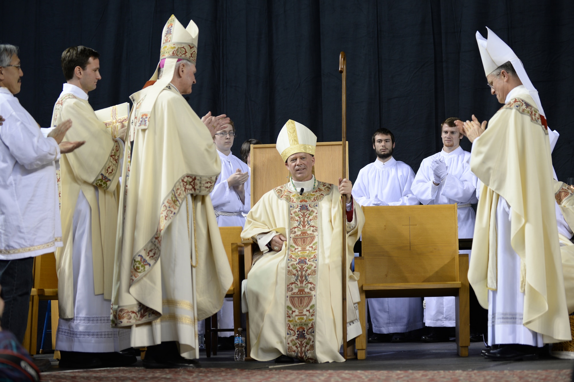 Fellow bishops and priests clap for Chaplain (Maj.) Chad Zielinski, the 354th Fighter Wing deputy wing chaplain, after being ordained the bishop of the Fairbanks Catholic diocese Dec. 15, 2014 at the Carlson Center, Fairbanks, Alaska. This is the first time an active-duty Airman has been chosen for a position of this magnitude. (U.S. Air Force photo by Staff Sgt. Shawn Nickel/Released)