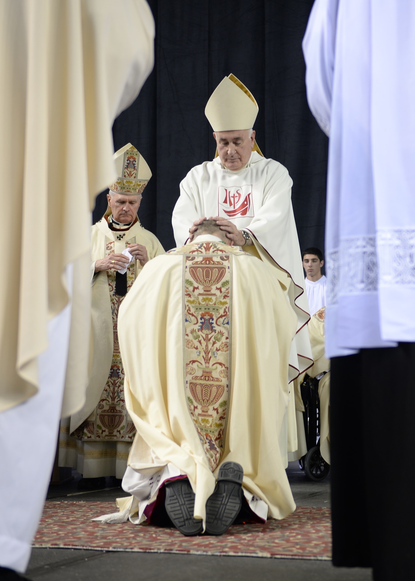 A fellow Catholic bishop lays hands on Chaplain (Maj.) Chad Zielinski, the 354th Fighter Wing deputy wing chaplain, ordaining Zielinski the bishop of the Fairbanks Catholic diocese Dec. 15, 2014 at the Carlson Center, Fairbanks, Alaska. By this ritual the ordaining bishops invoke the Holy Spirit to come down upon the one being ordained. (U.S. Air Force photo by Staff Sgt. Shawn Nickel/Released) 