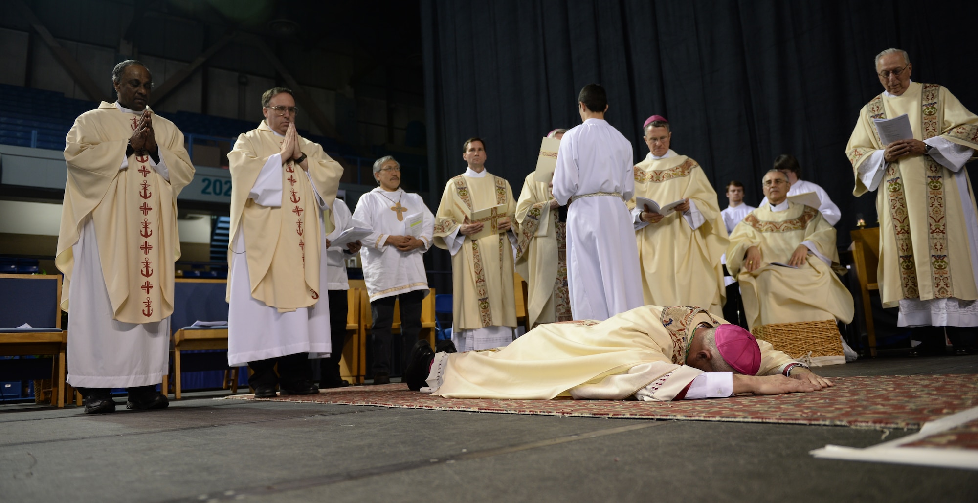 Chaplain (Maj.) Chad Zielinski, the 354th Fighter Wing deputy wing chaplain, prostrates himself in front of praying bishops and a crowd during a ceremony ordaining him the bishop of the Fairbanks Catholic diocese Dec. 15, 2014 at the Carlson Center, Fairbanks, Alaska. The ordained lies prostrate symbolizing his unworthiness for the office to be assumed and his dependence upon God and the prayers of the community. (U.S. Air Force photo by Staff Sgt. Shawn Nickel/Released)
