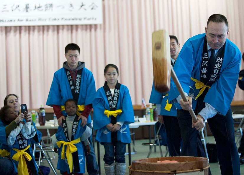 U.S. Air Force Col. Timothy Sundvall, 35th Fighter Wing commander, swings a wooden mallet as his family looks on, during the annual Mochi Pounding Ceremony at a Japan Air-Self Defense Force facility at Misawa Air Base, Japan, Dec. 15, 2014. Mochi, or rice cake, is traditionally made to celebrate the New Year. As the process of making this treat is considered difficult, it is done every year as a symbol of the teamwork and strong ties between America and Japan. (U.S. Air Force photo by Staff Sgt. Tong Duong/Released.) 

