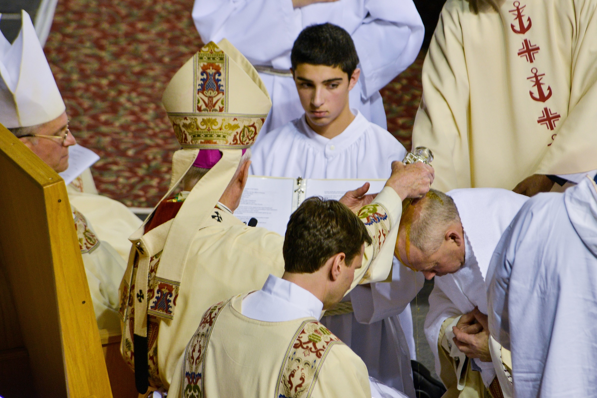 Rev. Roger L. Schwietz, Archbishop of Anchorage, Alaska, pours anointing oil on the head of Chaplain (Maj.) Chad Zielinski, the 354th Fighter Wing deputy wing chaplain, ordaining Zielinski the bishop of the Fairbanks Catholic diocese Dec. 15, 2014, at the Carlson Center, Fairbanks, Alaska. Zielinski will be responsible for overseeing Catholic interests in an area the size of Texas, much of which isn't accessible by road. (U.S. Air Force photo by Tech. Sgt. Joseph Swafford/Released)