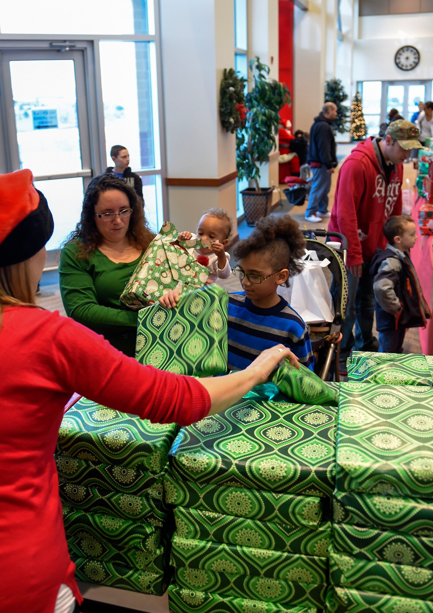 A volunteer hands out presents at the annual Breakfast with Santa event Dec. 14, 2014, at the Leadership Development Center on base. At the event, Team Buckley had the opportunity to meet Mr. and Mrs. Claus, grab a pancake breakfast and pick out their favorites from a variety of gifts to raise holiday spirit. (U.S. Air Force photo by Airman 1st Class Emily E. Amyotte/Released)