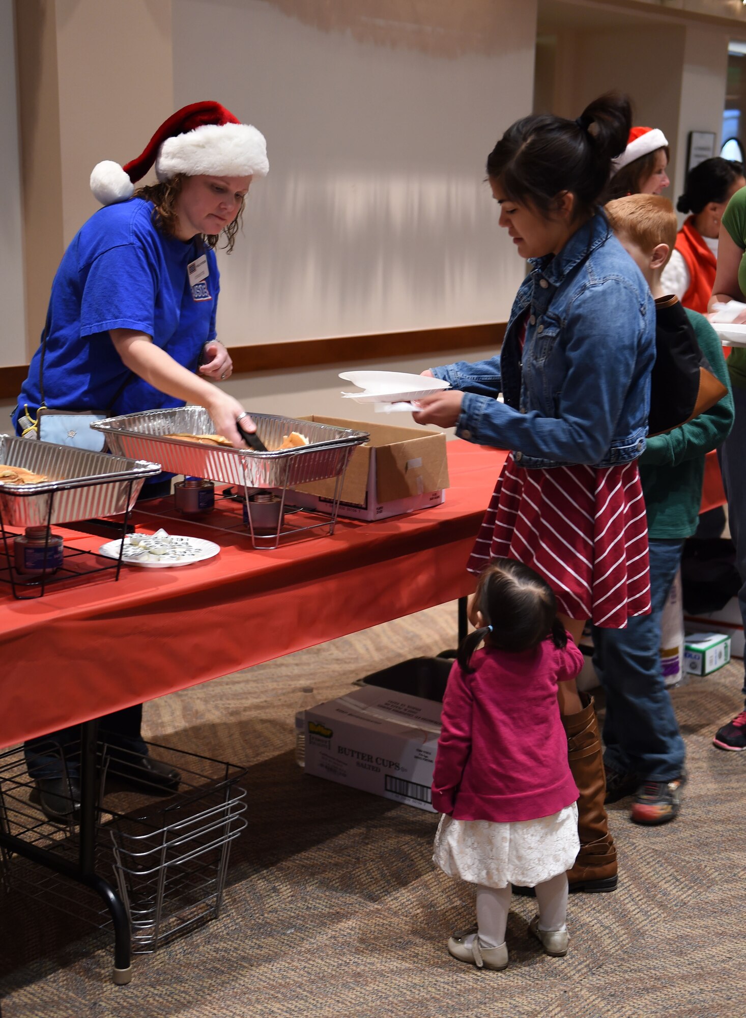A volunteer serves breakfast to Team Buckley members at the annual Breakfast with Santa event Dec. 14, 2014, at the Leadership Development Center on base. At the event, Team Buckley had the opportunity to meet Mr. and Mrs. Claus, grab a pancake breakfast and pick out their favorites from a variety of gifts to raise holiday spirit. (U.S. Air Force photo by Airman 1st Class Emily E. Amyotte/Released)