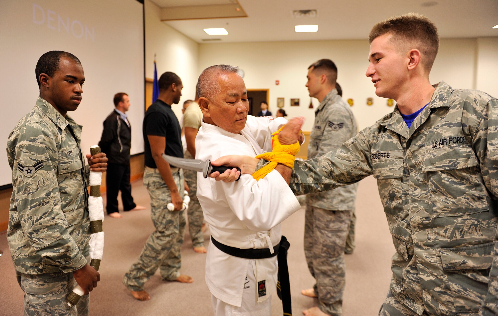 Takashi Nakamori, Bunbukan Karate instructor, demonstrates how to use a towel as protection from an attack by U.S. Air Force Airman 1st Class Shane Roberts, 18th Force Support Squadron employments technician, after an Okinawa cultural seminar on Kadena Air Base, Japan, Dec. 12, 2014. The Okinawa cultural seminar was an opportunity to educate and inform attendees of Okinawa history and culture. They also had an opportunity to see and participate in a Karate demonstration. (U.S. Air Force photo by Naoto Anazawa/Released)